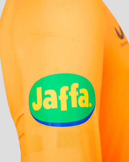 Close-up of an orange soccer jersey featuring a large green oval Jaffa logo with yellow lettering and a blue outline on the front, with a dark Adidas trefoil logo on the sleeve.