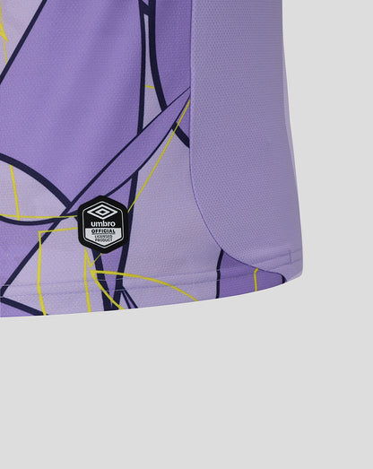 Close-up of a purple athletic jersey with a geometric black and yellow line pattern and a visible Umbro logo patch near the hem, set against a light gray background.