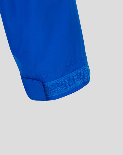 Close-up detail of a bright blue garment cuff with a hook-and-loop strap closure, shown against a light gray background.
