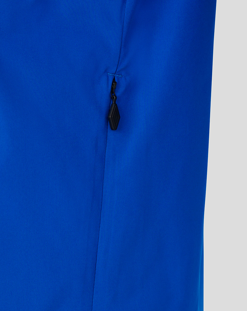 Close-up of a bright royal blue garment with a small black zipper pull on a light gray background.
