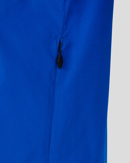 Close-up of a bright royal blue garment with a small black zipper pull on a light gray background.