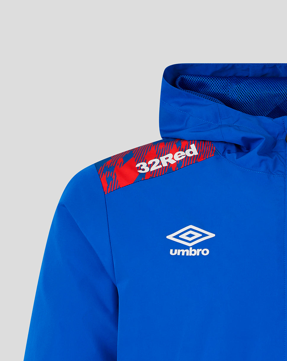 Close-up of a bright blue hooded jacket with a red and black patterned shoulder patch featuring the text '32Red' and a white Umbro logo on the chest.