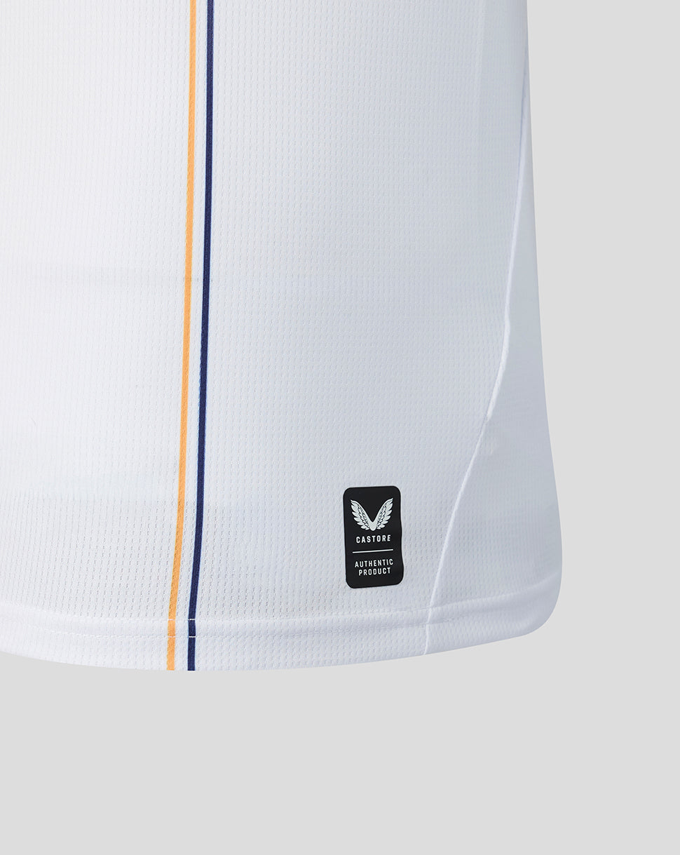 Close up of lower side of white away shirt showing navy and orange stripes and Castore authentic product label.