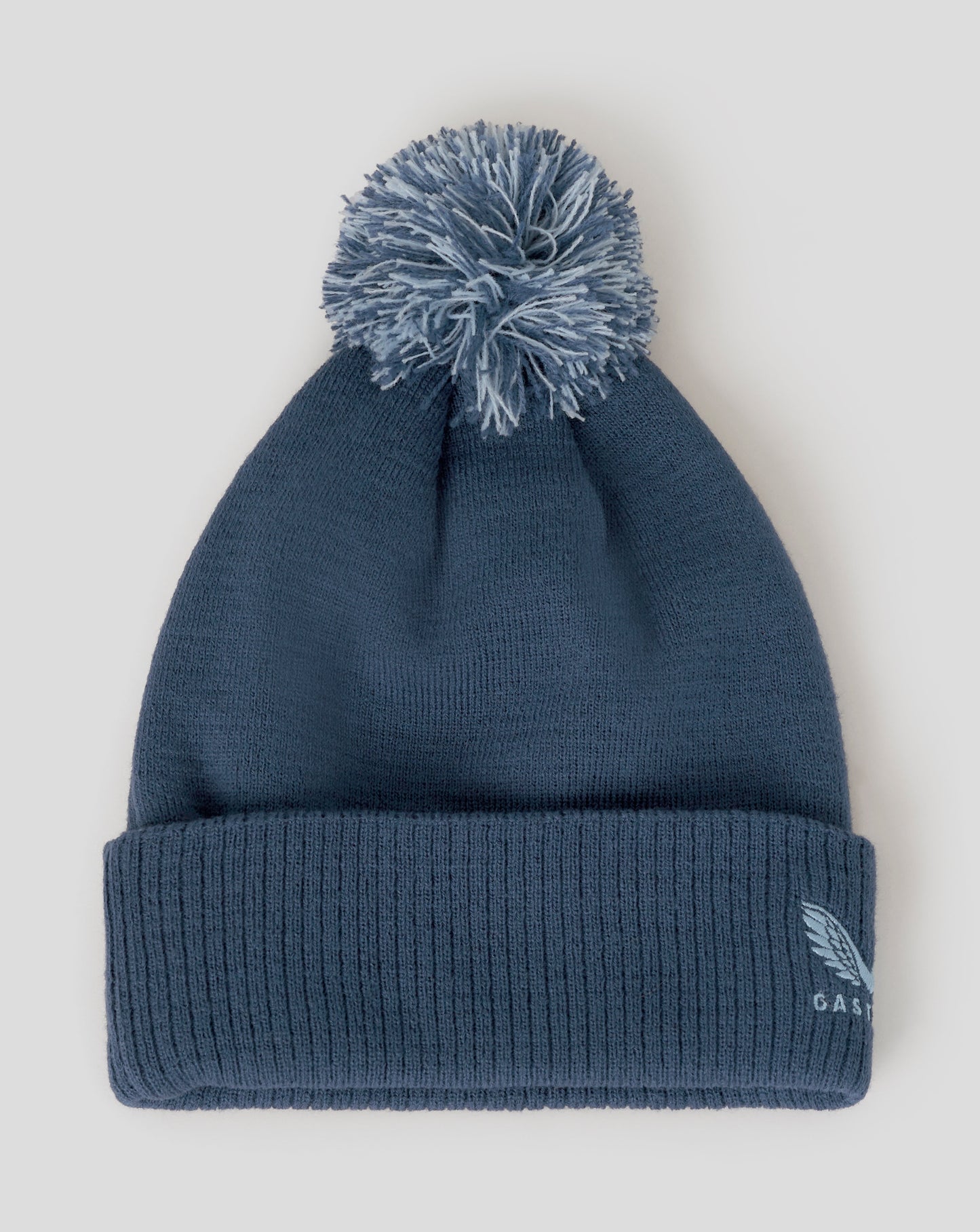 Blue beanie with pom-pom on a light gray background