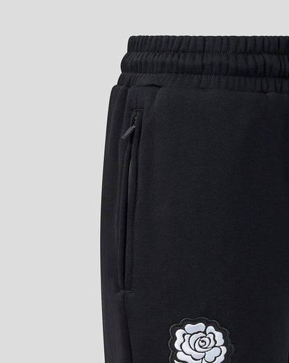 Black sweatpants with a white rose design on a light gray background