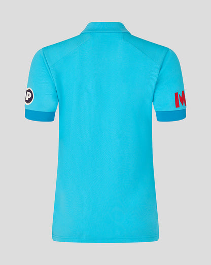 Blue polo shirt with brand logos on sleeves against a gray background