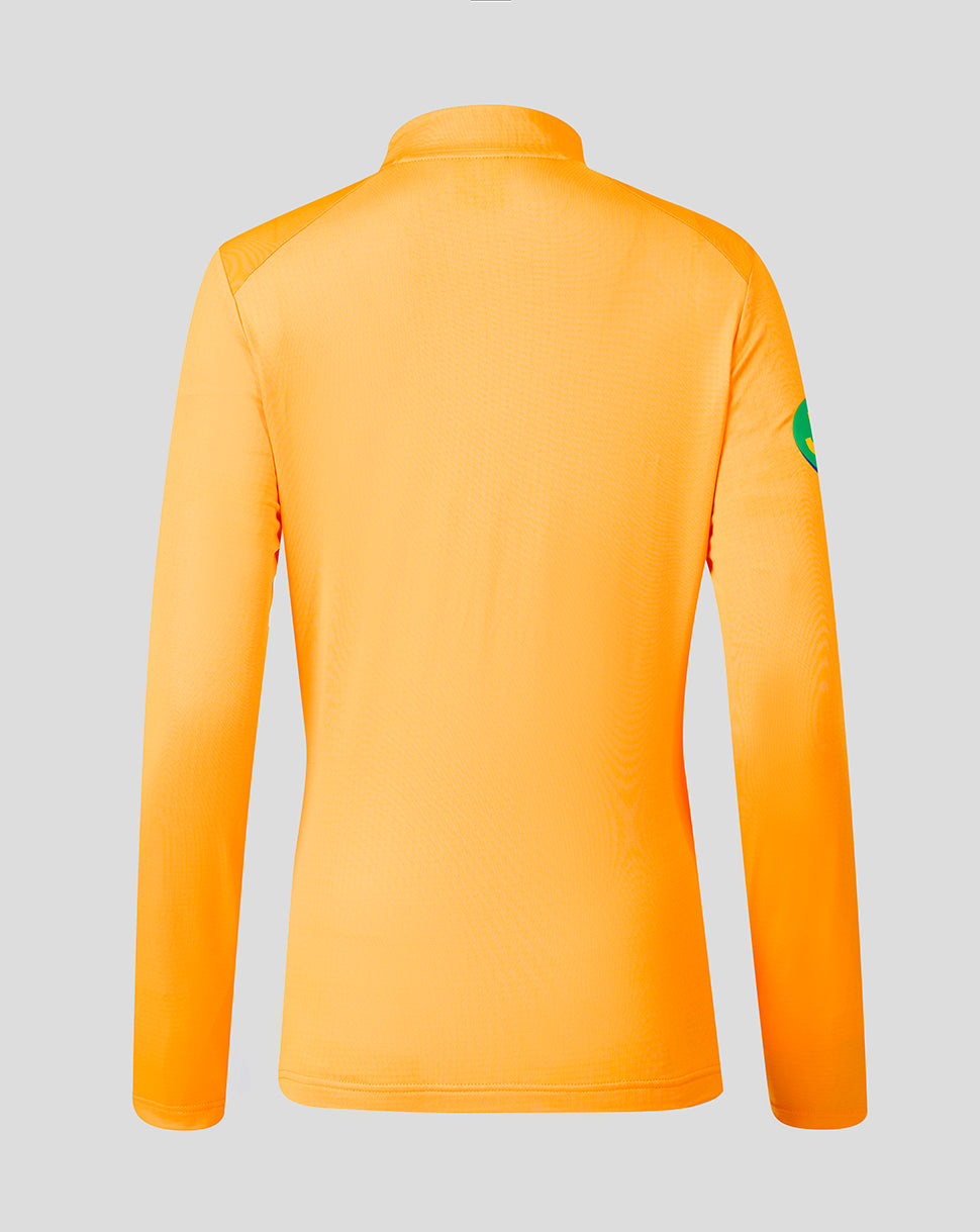 Bright orange long-sleeve athletic top shown from the back on a light gray background, with a small green patch on the upper right sleeve.