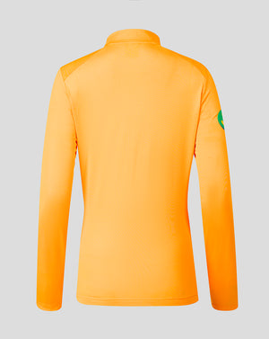 Bright orange long-sleeve athletic top shown from the back on a light gray background, with a small green patch on the upper right sleeve.