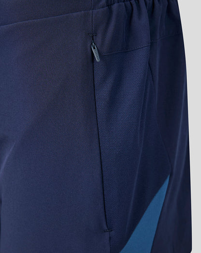 Navy blue pants with a pocket detail on a light gray background