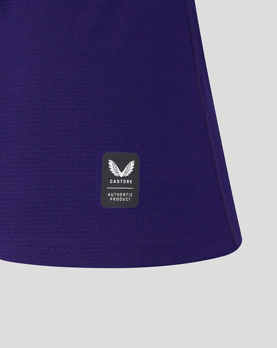 Close-up of a purple garment with a visible brand label on a light gray background