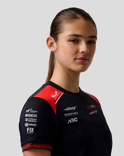 Person wearing a black and red sports jersey with various sponsor logos on a gray background