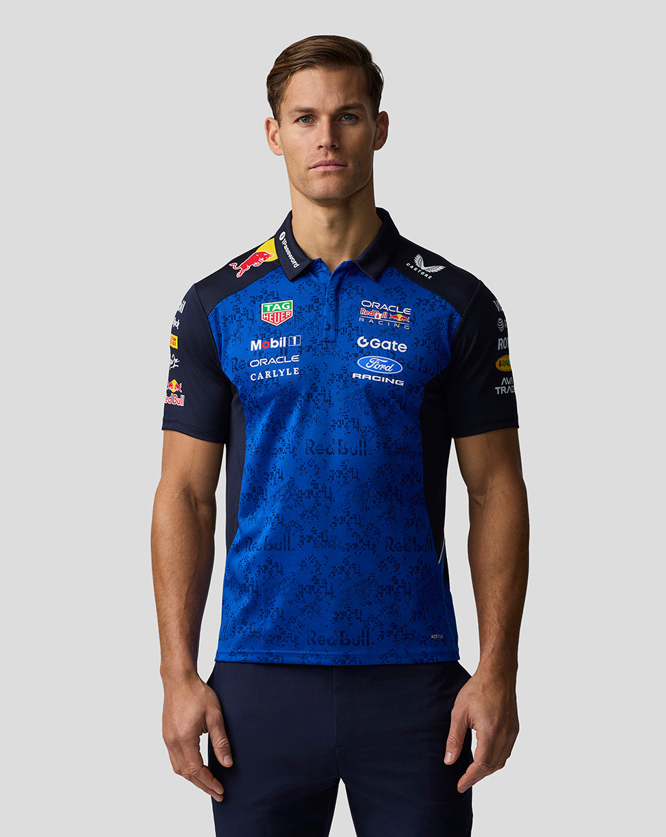 Man wearing a blue racing jersey with various sponsor logos on a gray background