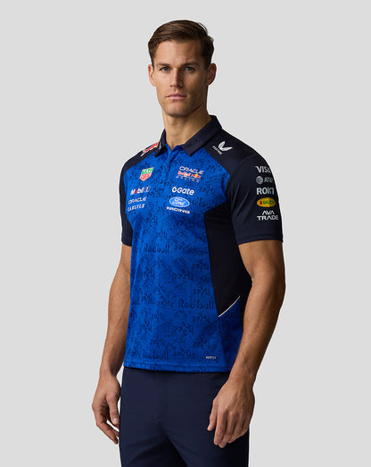 Man wearing a blue and black sports jersey with various sponsor logos on a gray background