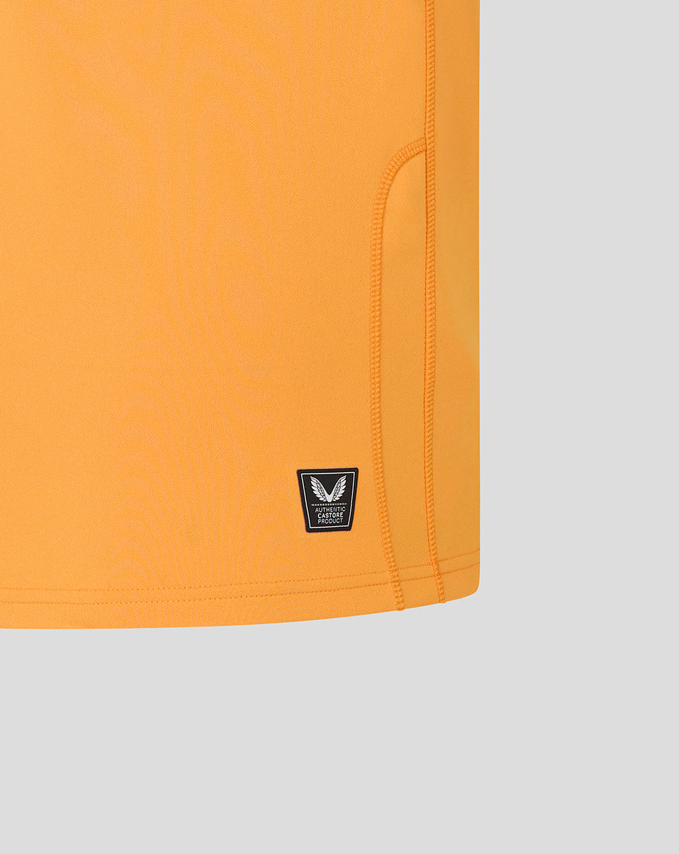 Close-up of an orange garment with a brand logo on a light gray background