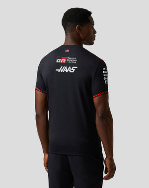 Person wearing a black Haas Formula One team shirt with logos on a gray background