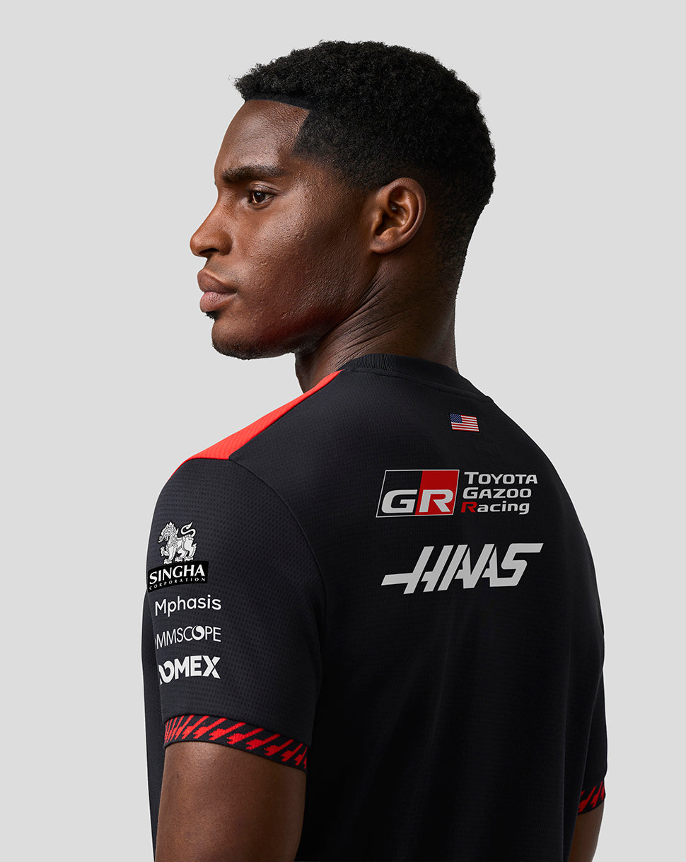 Person wearing a black racing jersey with various sponsor logos on a gray background