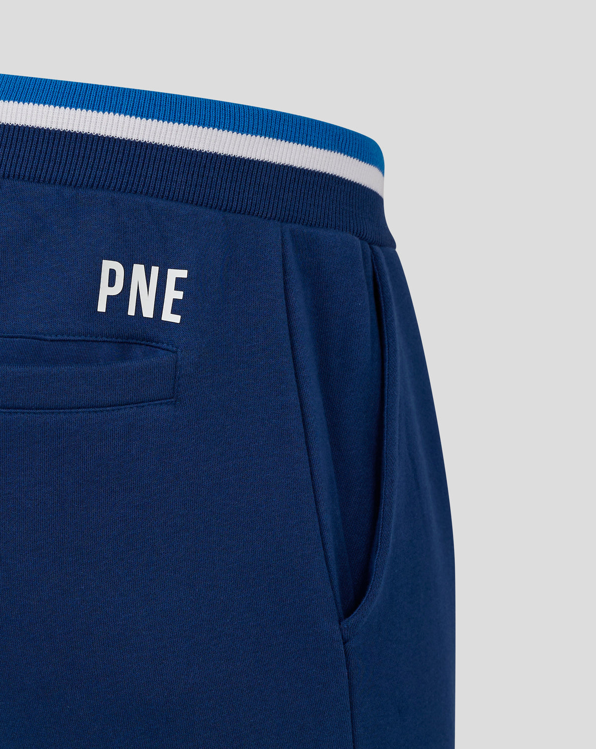 Close-up of navy jogger waistband showing blue rib knit with white stripe and back pocket seam