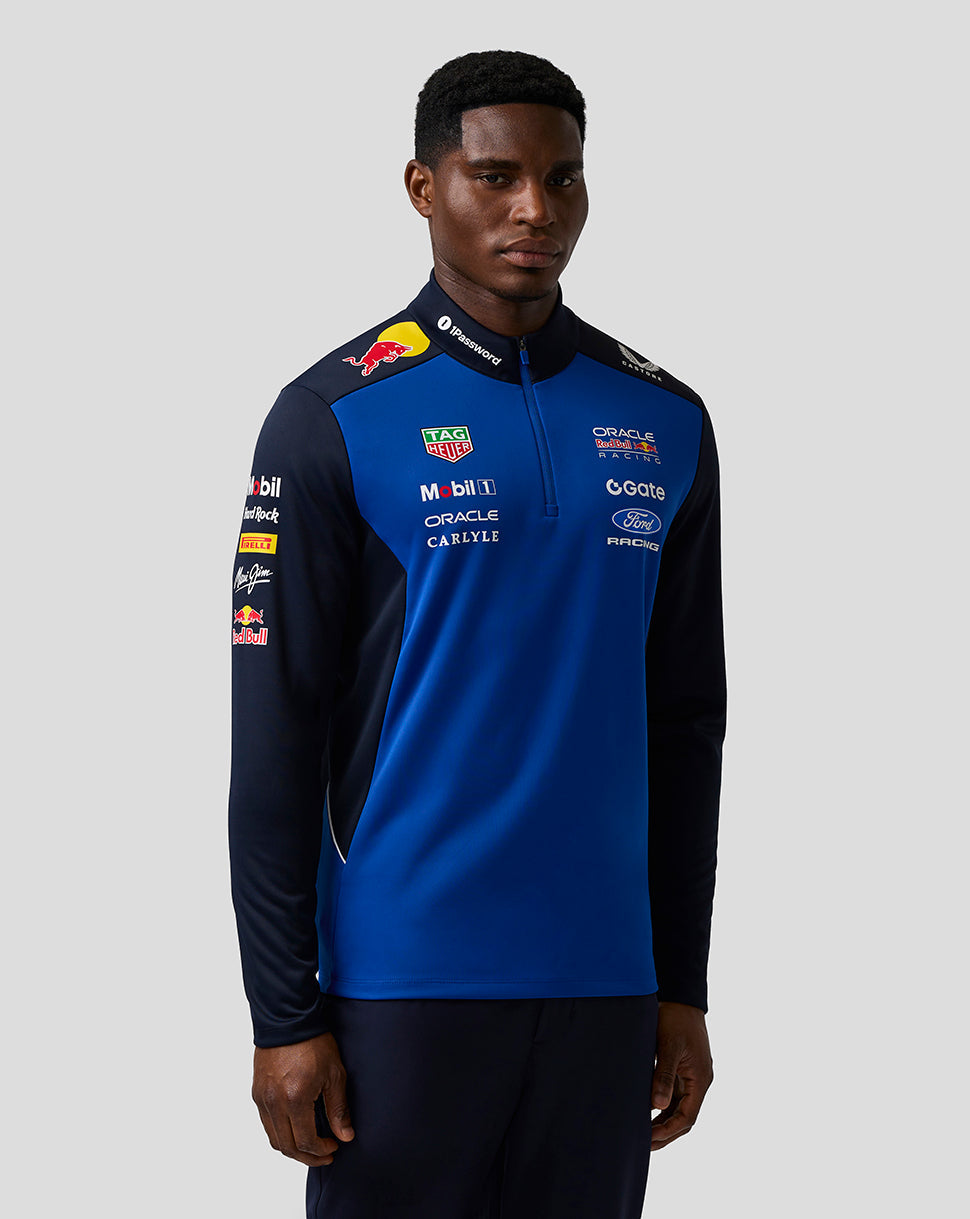 Person wearing a blue and black racing jacket with various sponsor logos on a gray background