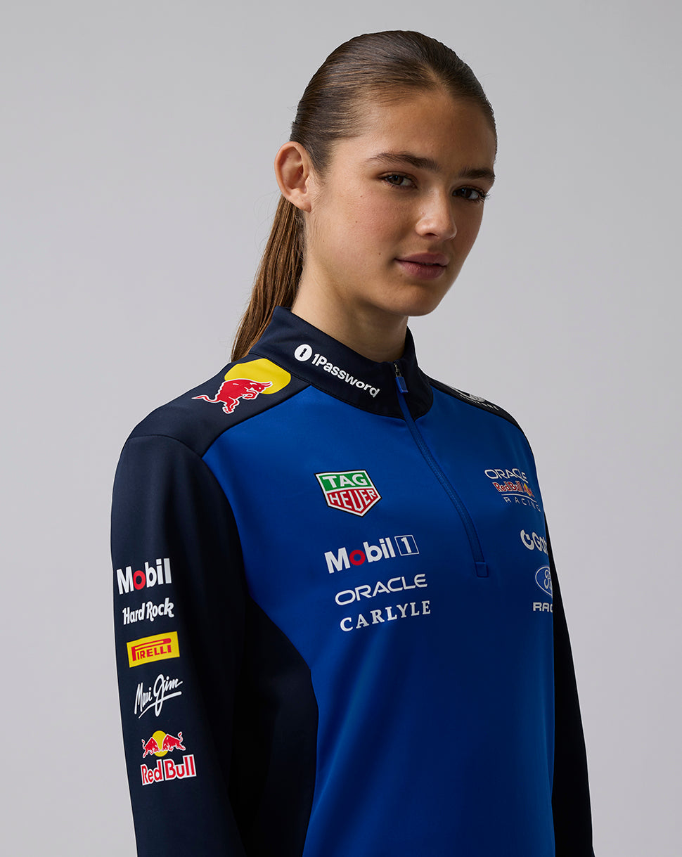 Person wearing a blue racing suit with various sponsor logos on a gray background