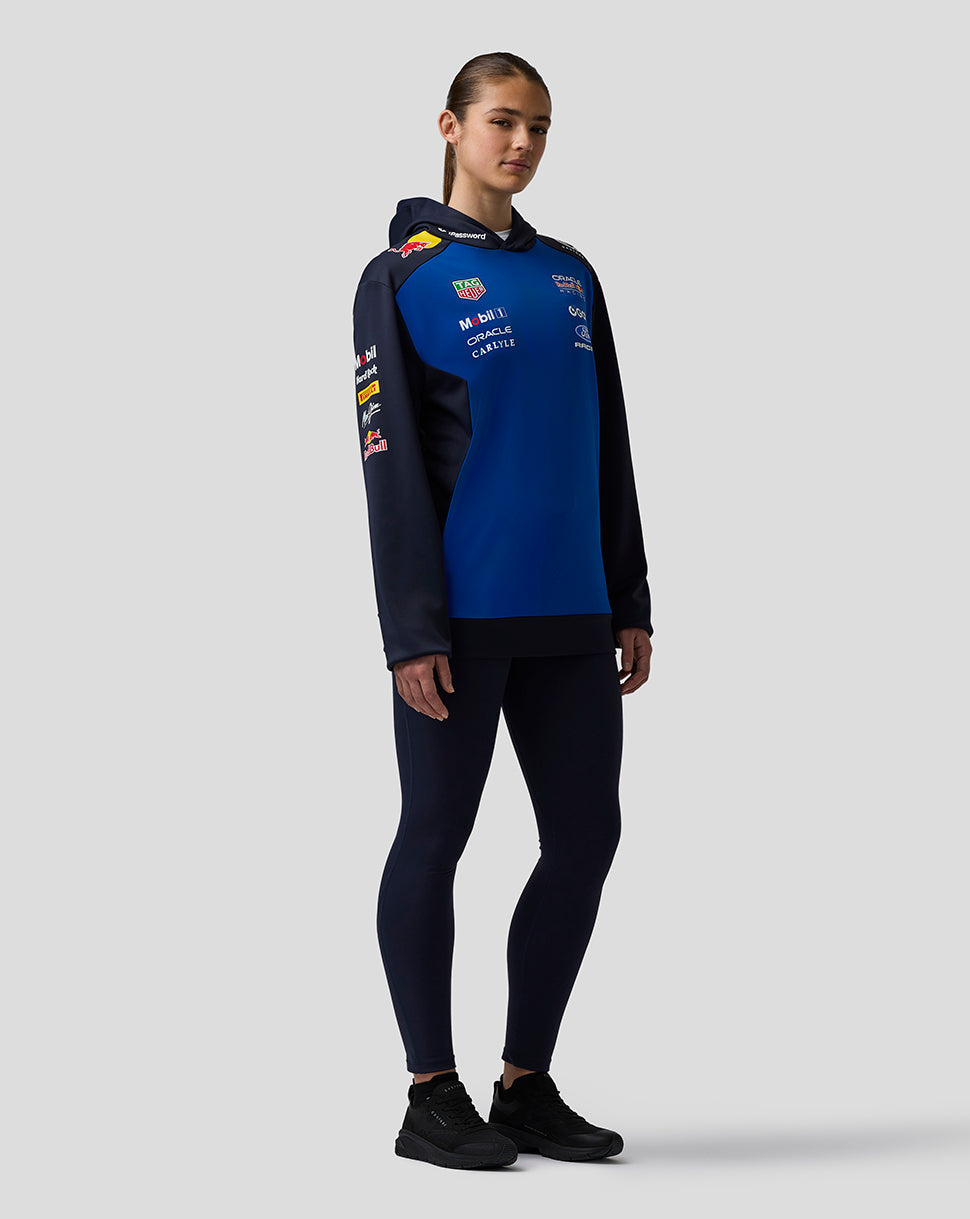 Person wearing a blue and black hoodie with sponsor logos on a gray background