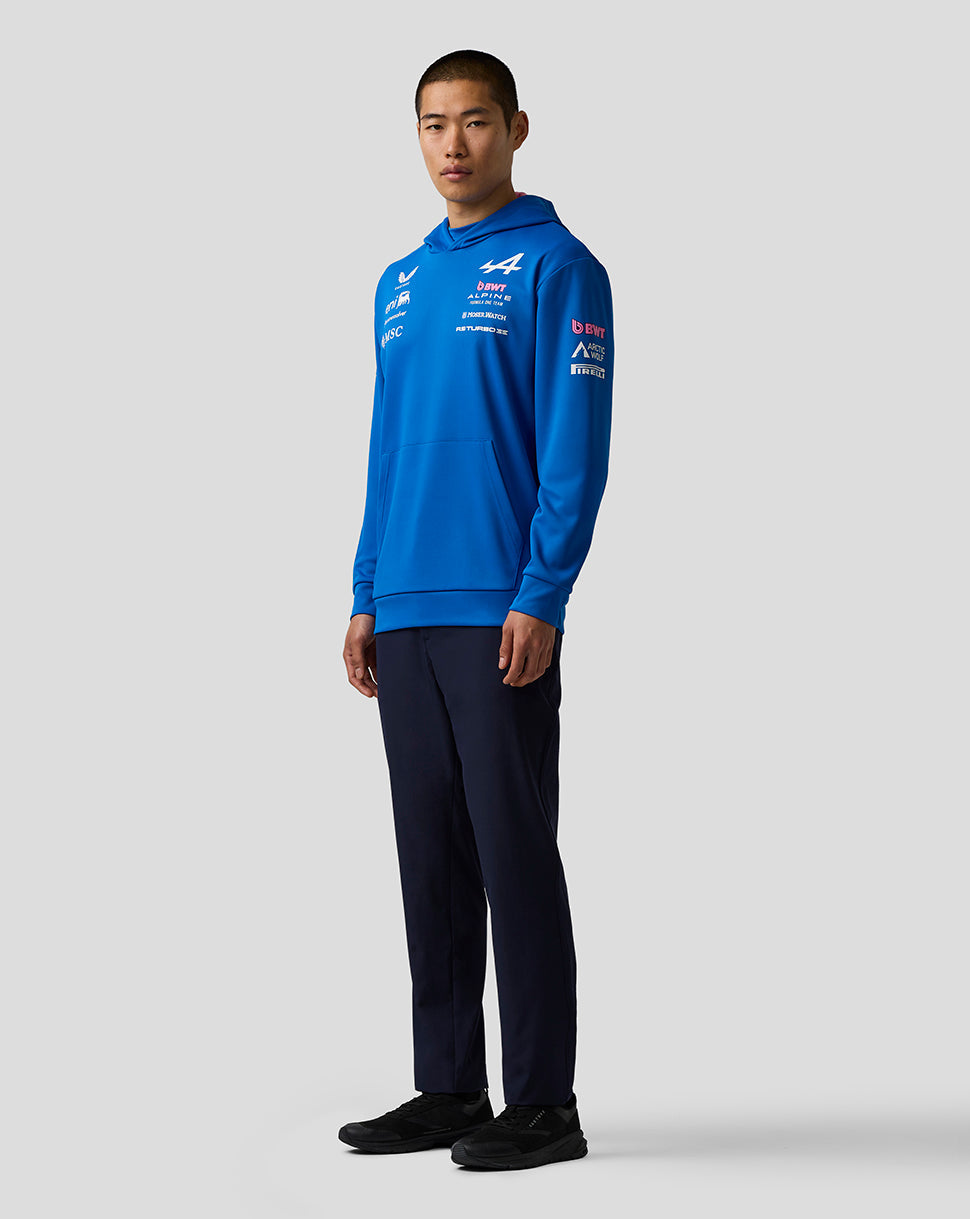 Person wearing a blue hoodie with logos on a light gray background