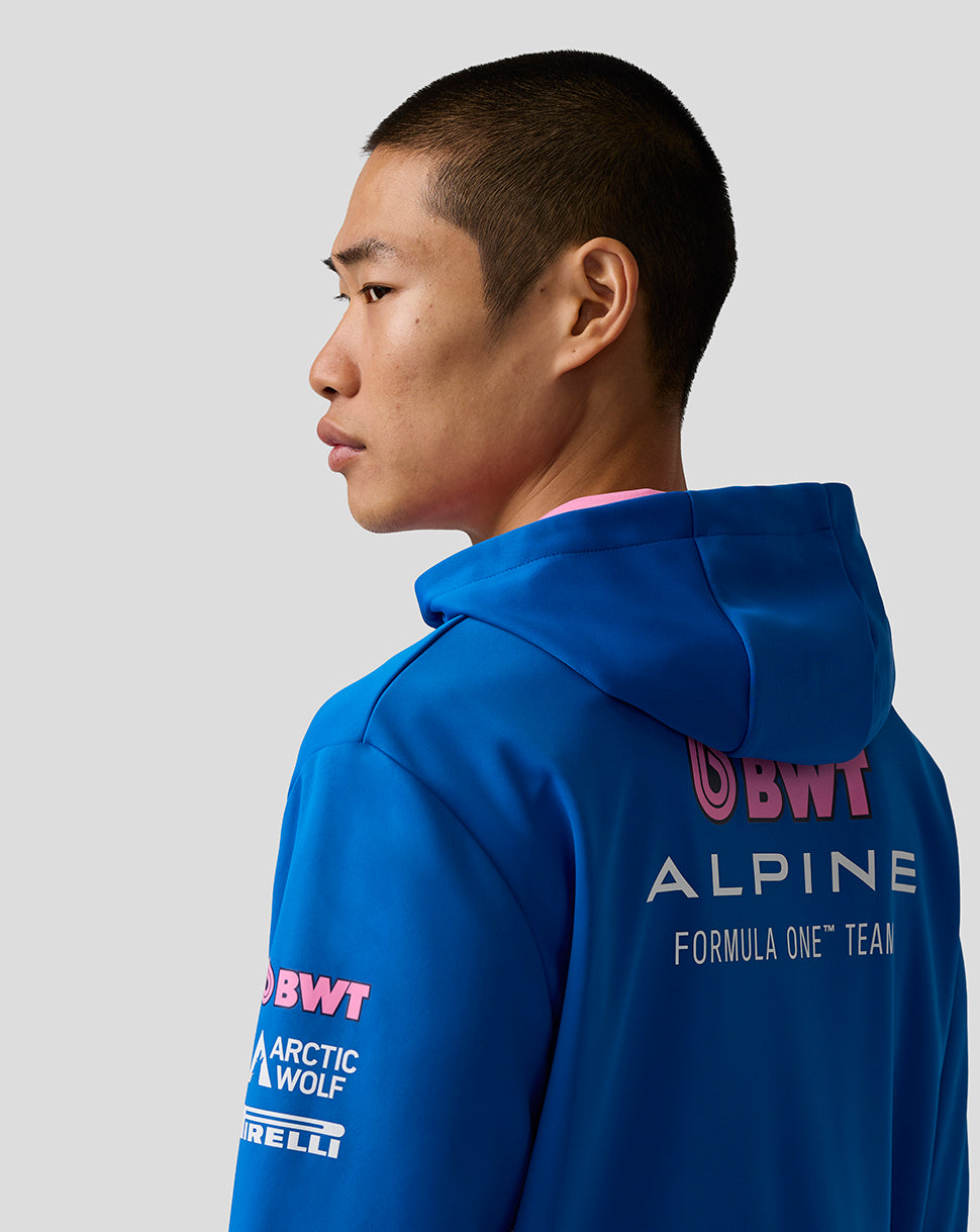 Person wearing a blue hoodie with branding on the back against a gray background