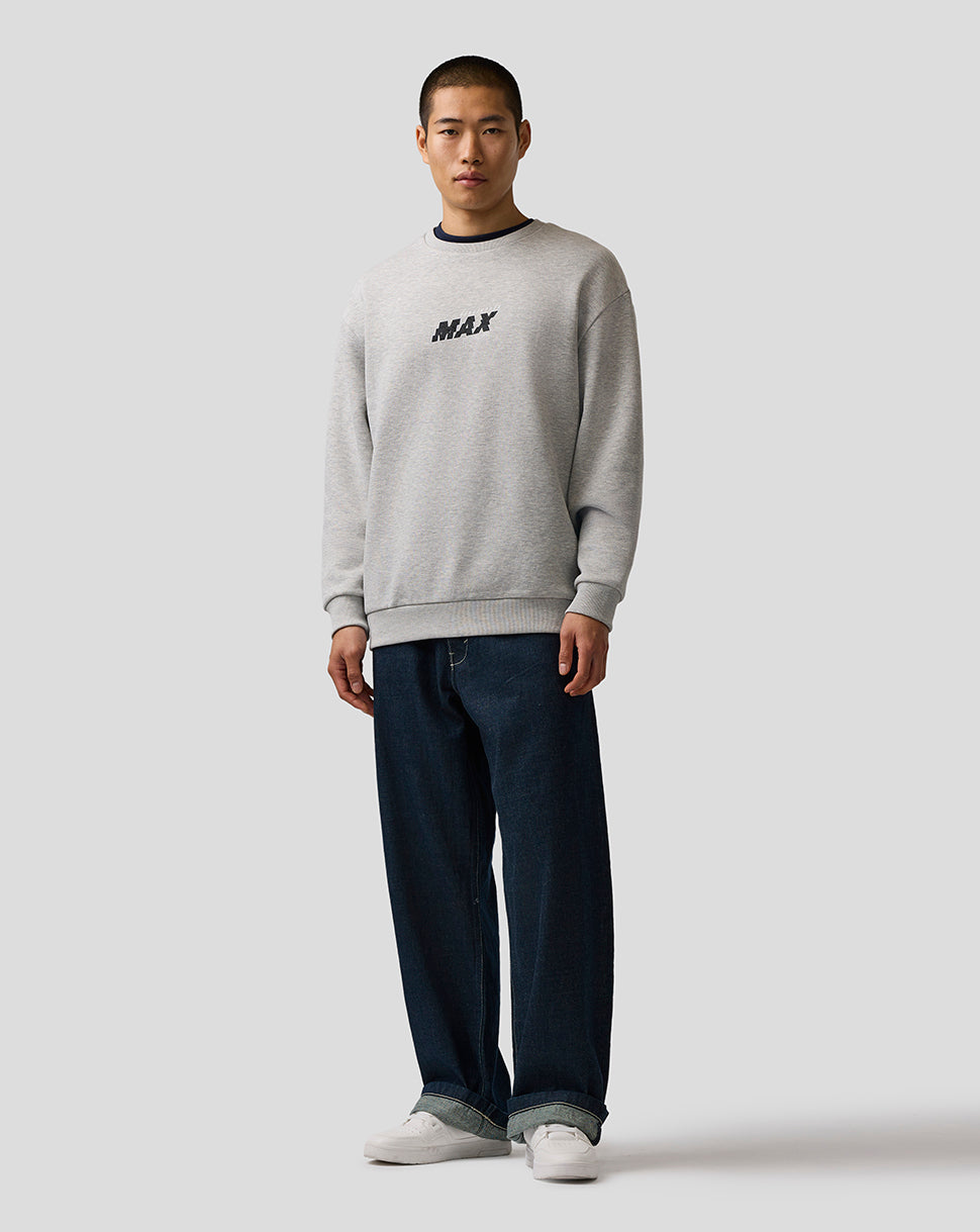 Man wearing a gray sweatshirt with 'MAX' text and dark jeans on a white background