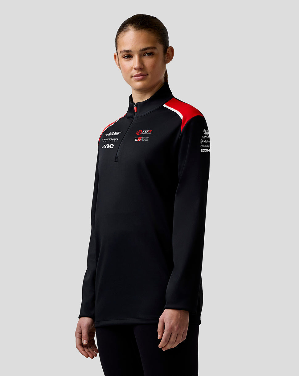 Person wearing a black long-sleeve shirt with red and white accents on a gray background