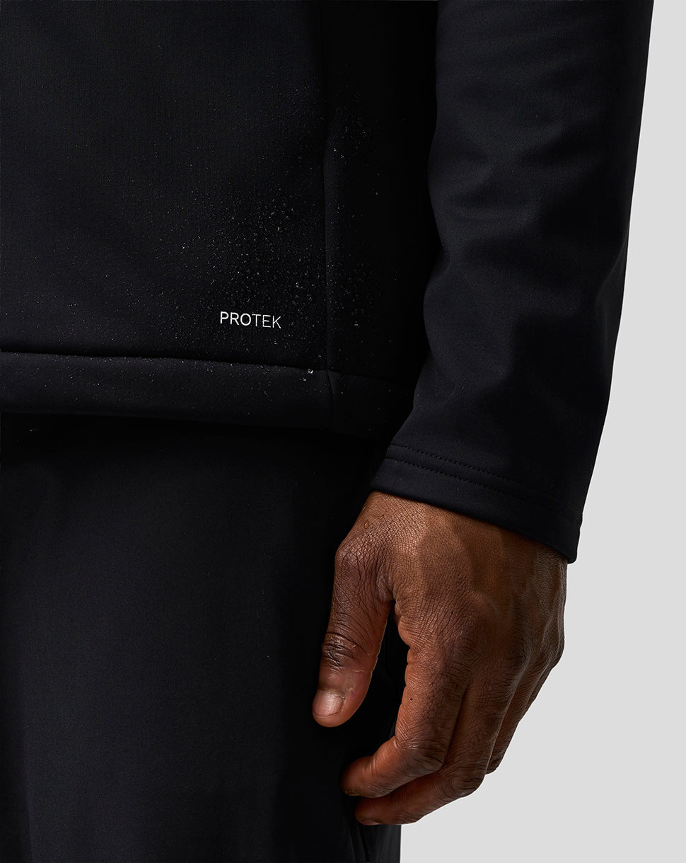 Close-up of a person wearing a black jacket with 'PROTEK' branding on a light gray background