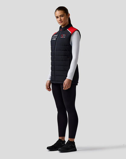 Person wearing a black puffer vest with red accents on a gray background