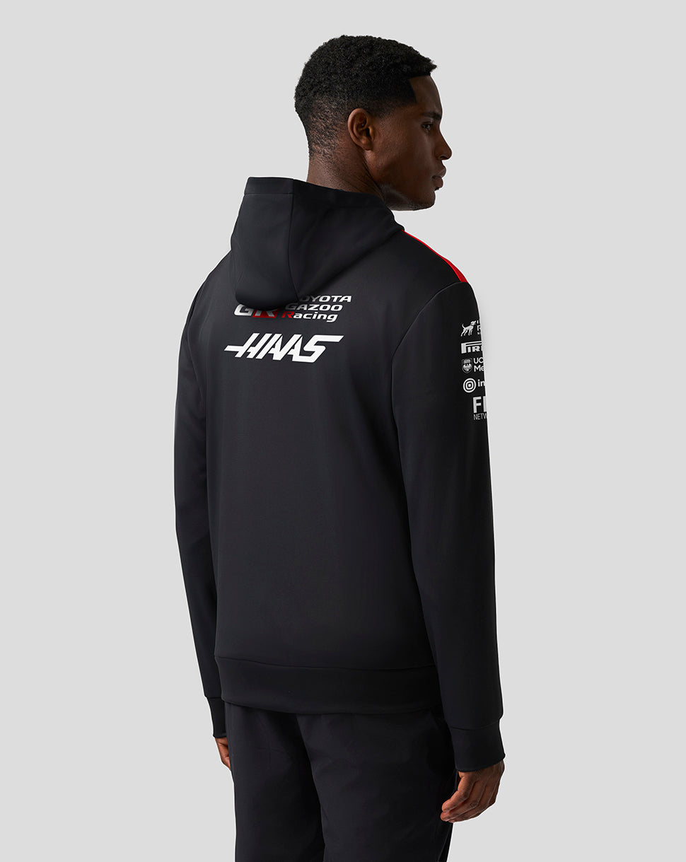 Person wearing a black hoodie with branding on the back against a gray background