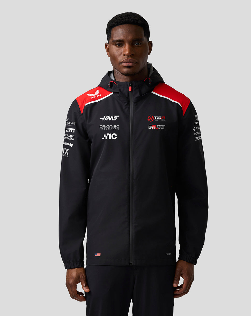 Person wearing a black jacket with red and white accents on a gray background