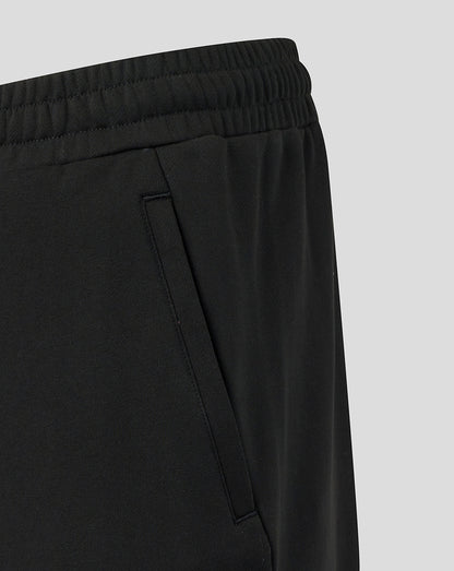Black pants with a focus on the waistband and side seam against a light gray background