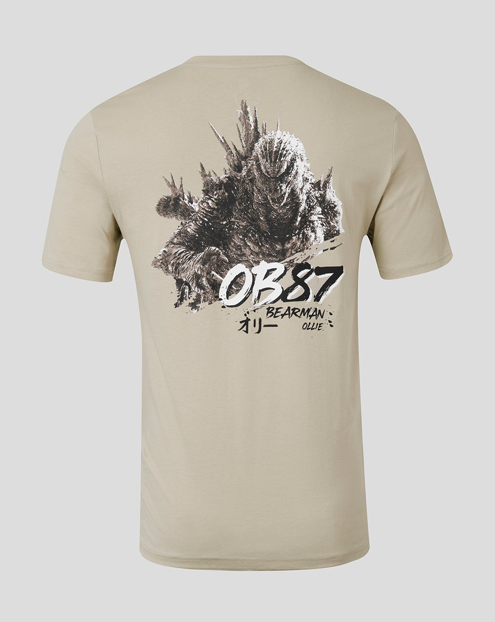 A beige short-sleeve t-shirt shown from the back, featuring a large black and white graphic print of Godzilla with the text 'OB87 BEARMAN' and Japanese characters.