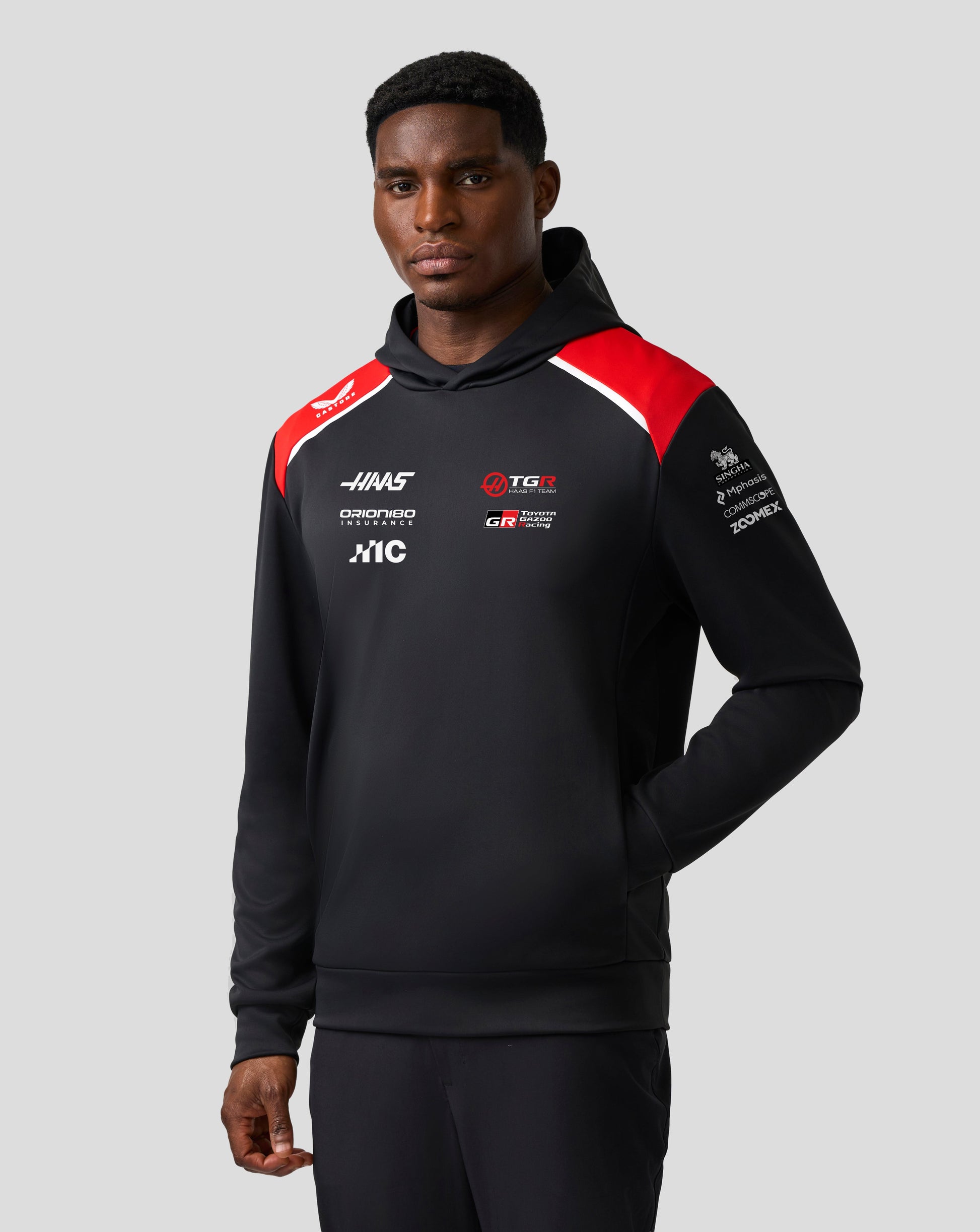 Person wearing a black hoodie with red and white accents on a gray background